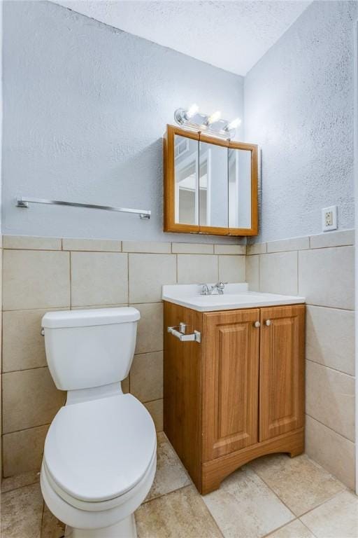 bathroom with tile walls, toilet, and vanity