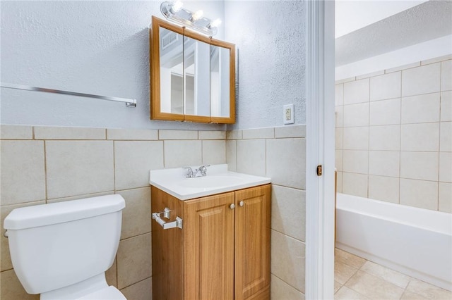 bathroom featuring tile walls, toilet, a tub to relax in, and vanity