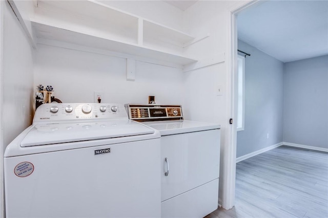 laundry area featuring independent washer and dryer, light wood-type flooring, and baseboards
