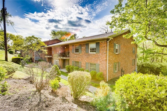 view of front of house featuring brick siding and a balcony