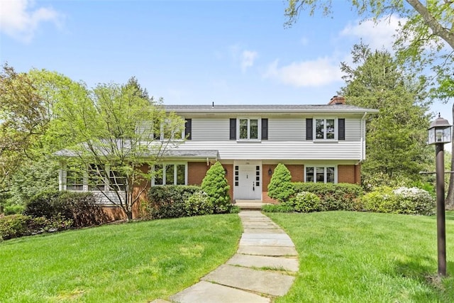 view of front of house featuring brick siding, a front lawn, and a chimney