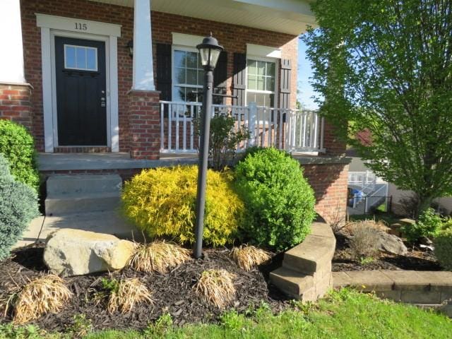 view of exterior entry featuring brick siding and covered porch