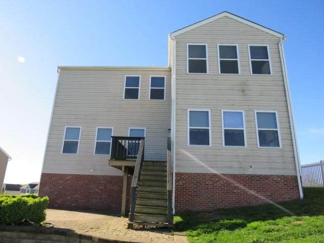 rear view of property with brick siding and stairs
