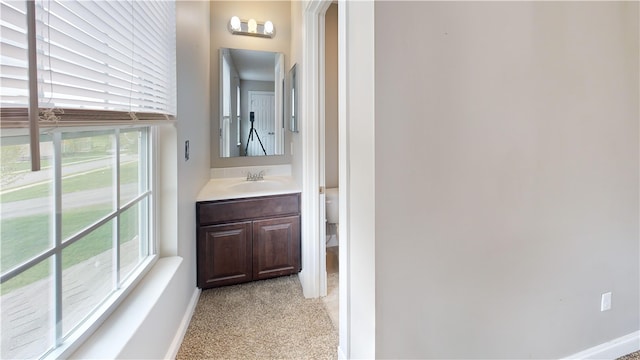 bathroom featuring baseboards, vanity, and toilet