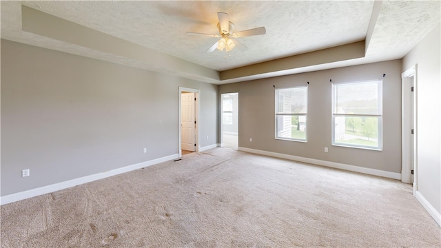 empty room with a textured ceiling, light carpet, baseboards, and ceiling fan
