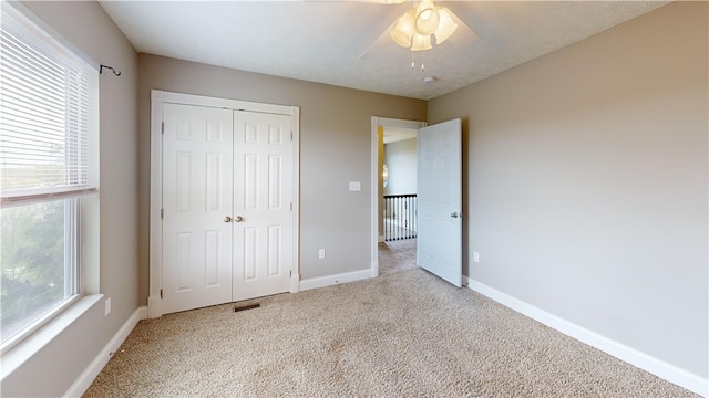 unfurnished bedroom with carpet, baseboards, a closet, and ceiling fan
