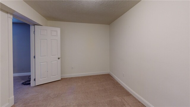 empty room with carpet flooring, a textured ceiling, and baseboards