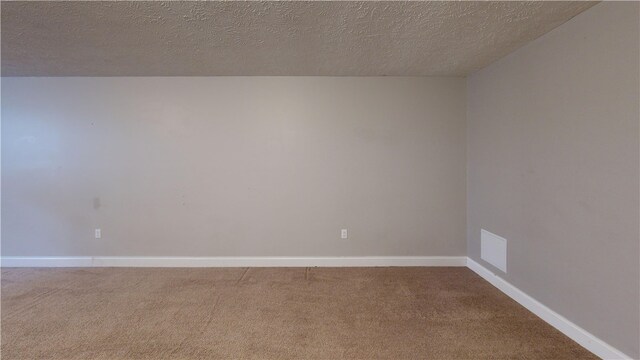 spare room with carpet floors, a textured ceiling, and baseboards