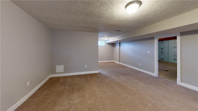 finished below grade area featuring a textured ceiling, carpet flooring, and baseboards
