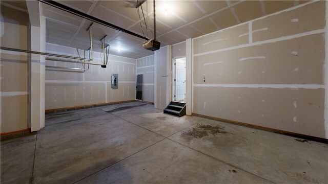 garage with a garage door opener, electric panel, and baseboards