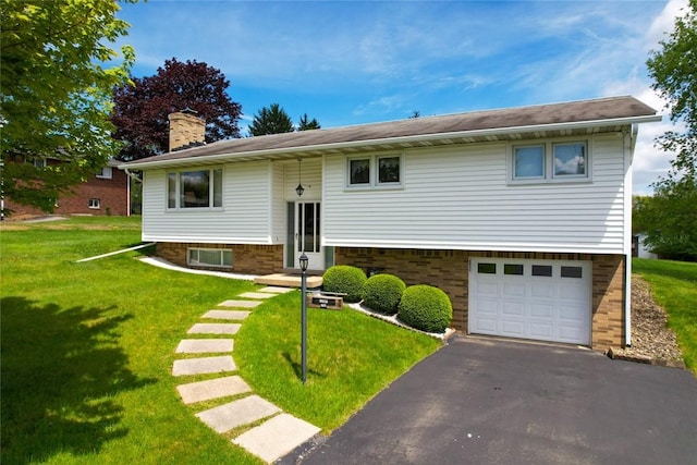 bi-level home featuring a chimney, a garage, a front yard, asphalt driveway, and brick siding