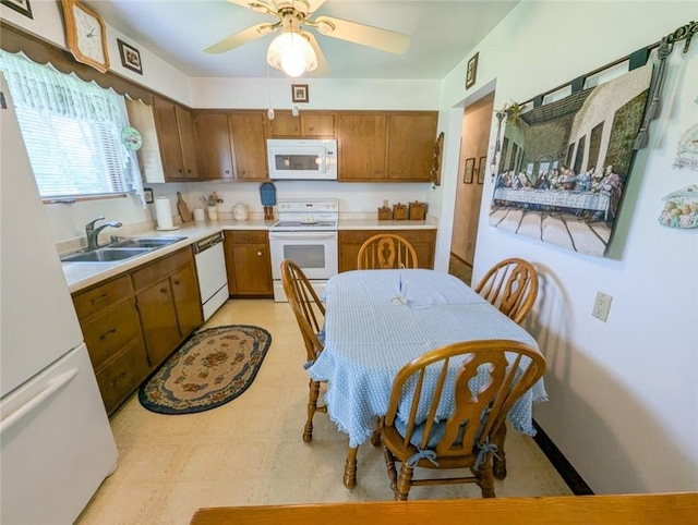 kitchen with white appliances, a sink, brown cabinetry, light countertops, and ceiling fan