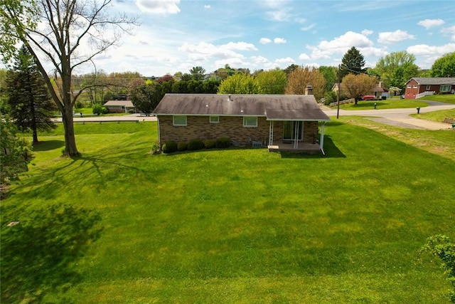 rear view of property with a chimney and a lawn