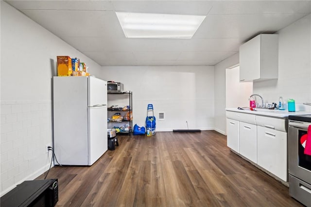 kitchen featuring freestanding refrigerator, a sink, stainless steel electric range oven, and white cabinets
