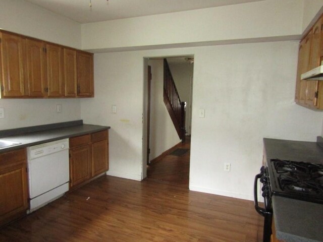 643 Indiana Ave, Glassport, PA 15045 - kitchen featuring white dishwasher, dark countertops, brown cabinets, dark wood-style floors, and under cabinet range hood