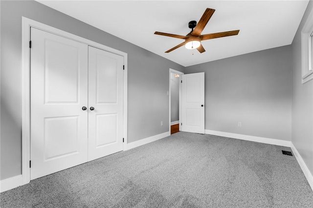 unfurnished bedroom featuring carpet, baseboards, a closet, and a ceiling fan