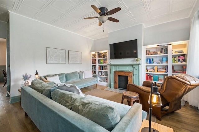 living room featuring an ornate ceiling, a ceiling fan, a fireplace with flush hearth, and dark wood finished floors