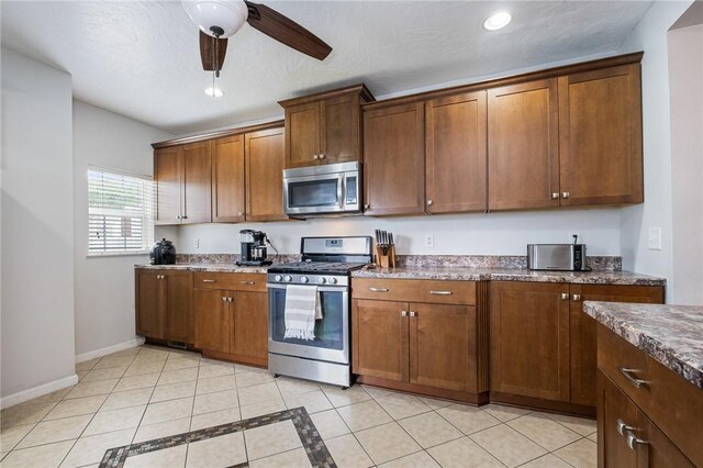 kitchen with appliances with stainless steel finishes, ceiling fan, dark stone counters, recessed lighting, and light tile patterned floors