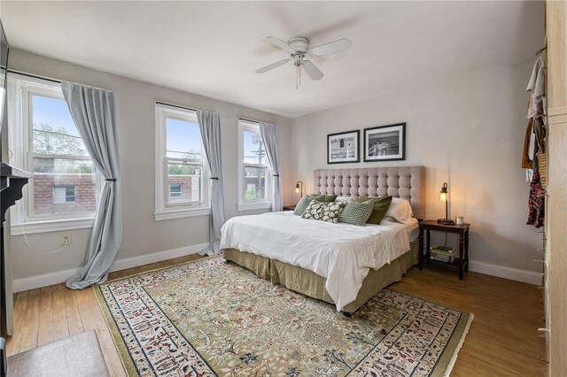 bedroom with wood finished floors, baseboards, and ceiling fan