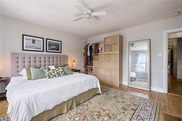 bedroom with wood finished floors, baseboards, and ceiling fan