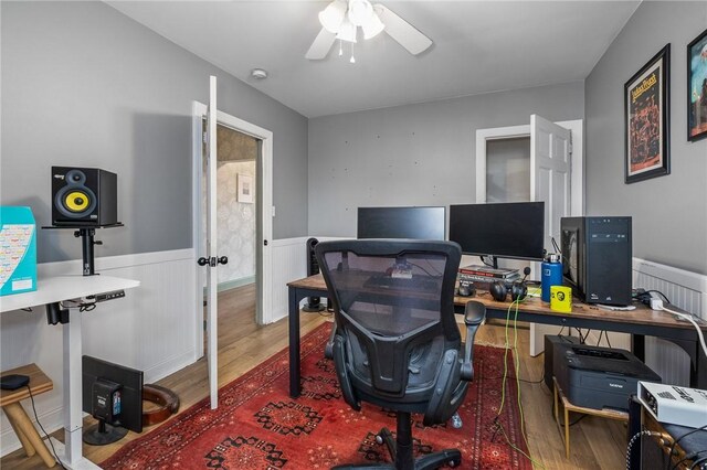home office with wood finished floors, a wainscoted wall, and a ceiling fan