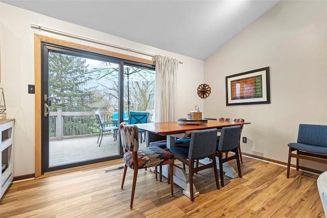 dining space with vaulted ceiling, light wood finished floors, and baseboards