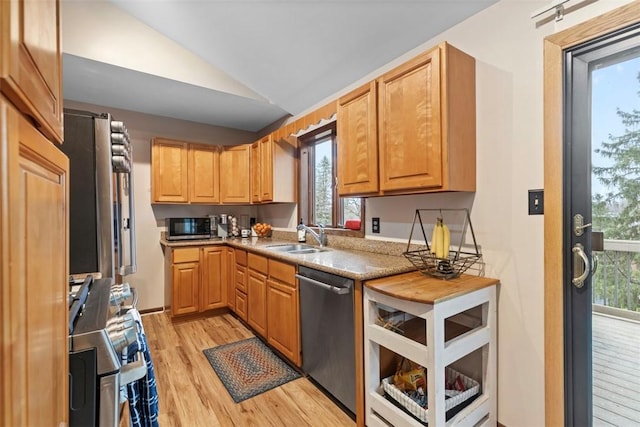 kitchen featuring stainless steel appliances, a sink, light wood-type flooring, lofted ceiling, and healthy amount of natural light