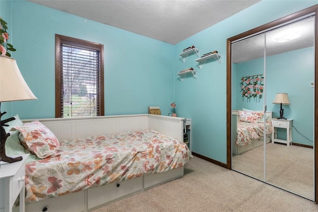 bedroom featuring a closet, carpet flooring, a textured ceiling, and baseboards