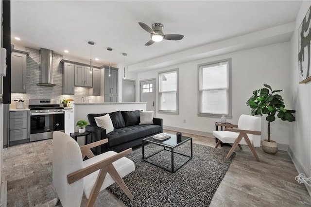 living area with a ceiling fan, baseboards, light wood-style floors, and recessed lighting