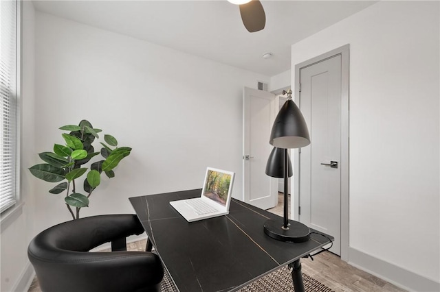 office space featuring light wood-type flooring, ceiling fan, and baseboards