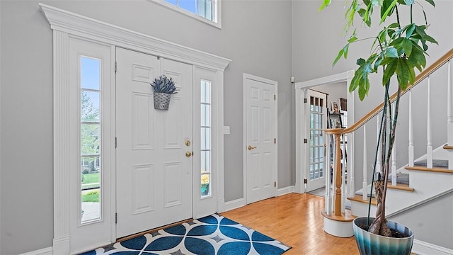 entryway with healthy amount of natural light, stairs, baseboards, and a high ceiling