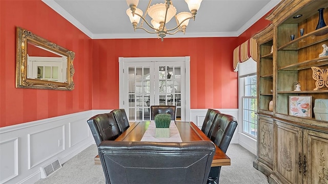 dining area featuring a chandelier, carpet, a wainscoted wall, a decorative wall, and crown molding