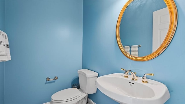 bathroom with a sink, toilet, and baseboards