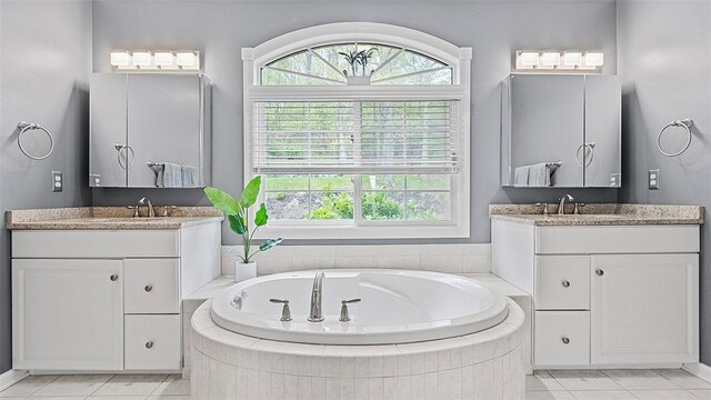 full bath with healthy amount of natural light, tile patterned flooring, and two vanities