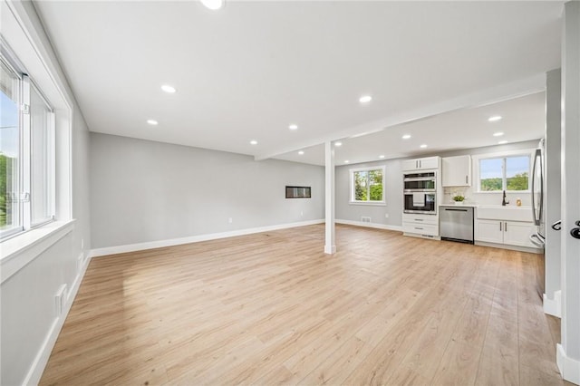 unfurnished living room featuring light wood finished floors, baseboards, recessed lighting, and a sink