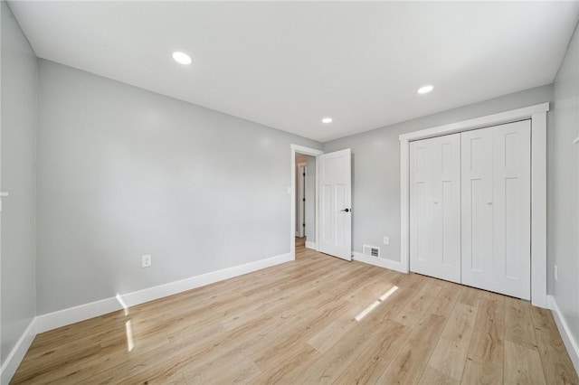 unfurnished bedroom featuring baseboards, light wood-style flooring, recessed lighting, and a closet