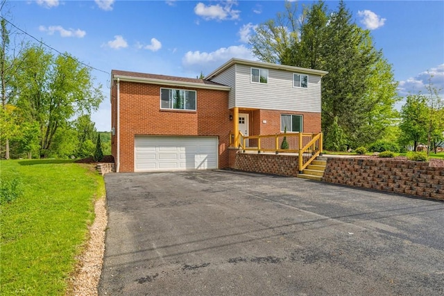 tri-level home featuring driveway, an attached garage, brick siding, and a front lawn