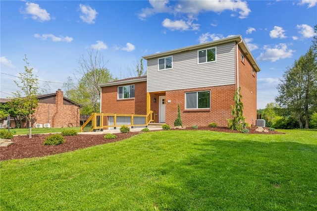 split level home with brick siding, a front yard, a deck, and central AC unit
