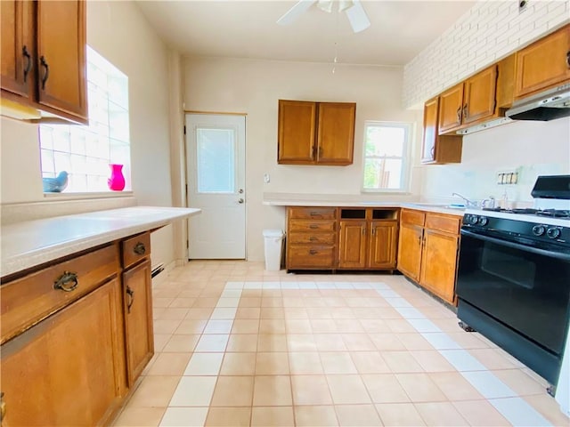 811 Farragut St, Highland Park, PA 15206 - kitchen with black gas range oven, under cabinet range hood, brown cabinetry, ceiling fan, and light countertops