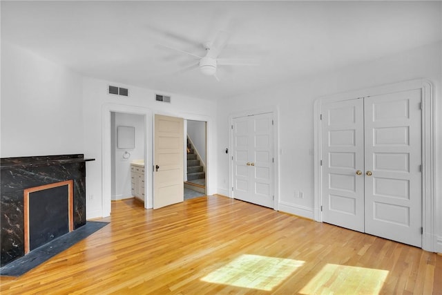 unfurnished living room featuring a fireplace, wood finished floors, a ceiling fan, baseboards, and stairs