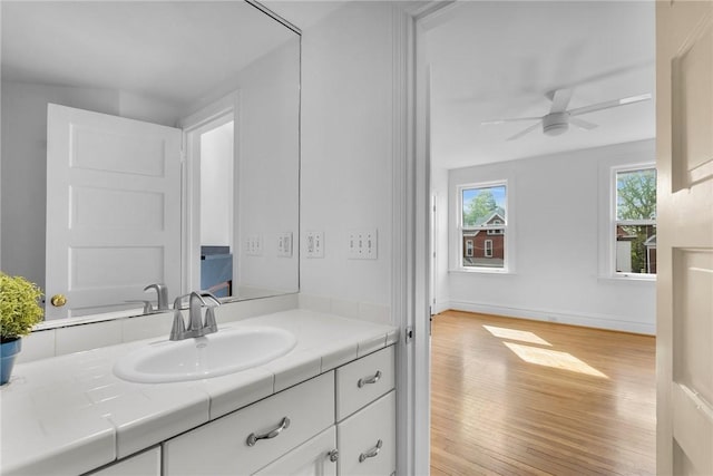 bathroom with wood finished floors, ceiling fan, vanity, and baseboards