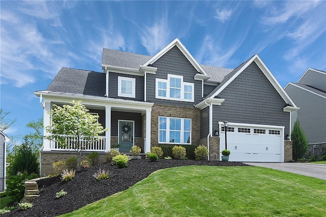 craftsman inspired home featuring asphalt driveway, a porch, a front lawn, roof with shingles, and brick siding