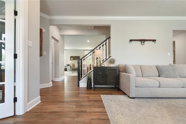 living area with crown molding, dark wood-style flooring, stairs, and baseboards