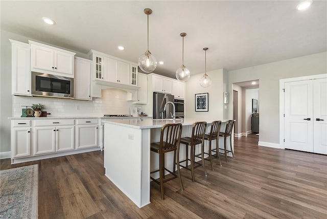 kitchen featuring stainless steel appliances, dark wood finished floors, decorative backsplash, light countertops, and recessed lighting