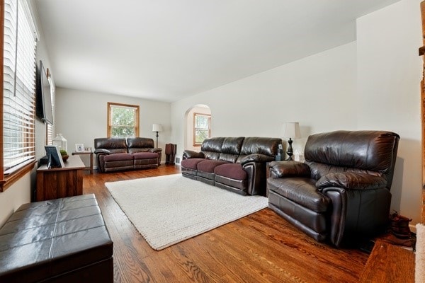 living area featuring arched walkways and wood finished floors