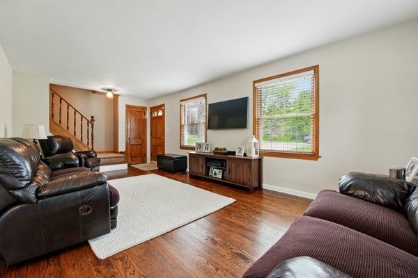 living area with stairway, wood finished floors, and baseboards