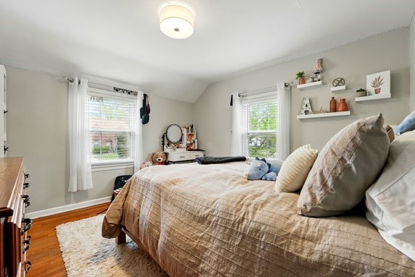 bedroom featuring wood finished floors, lofted ceiling, and baseboards
