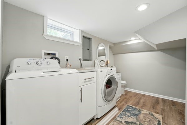 laundry area featuring light wood-style flooring, electric panel, washing machine and clothes dryer, recessed lighting, and baseboards