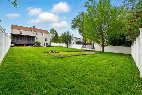 view of yard with a trampoline and a sunroom