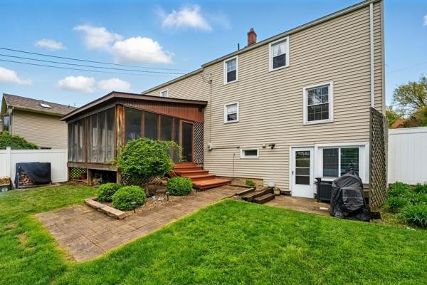rear view of property with a sunroom and a chimney
